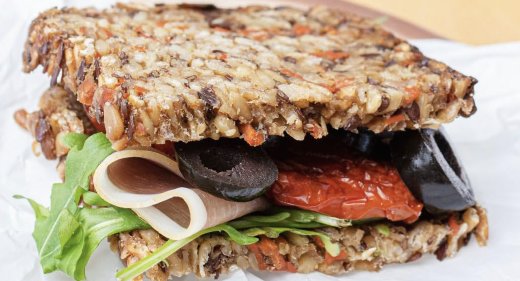 Slice of Mestemacher Low-Calorie Bread on a wooden cutting board, showcasing its hearty texture and whole grain ingredients, ideal for healthy meals and snacks